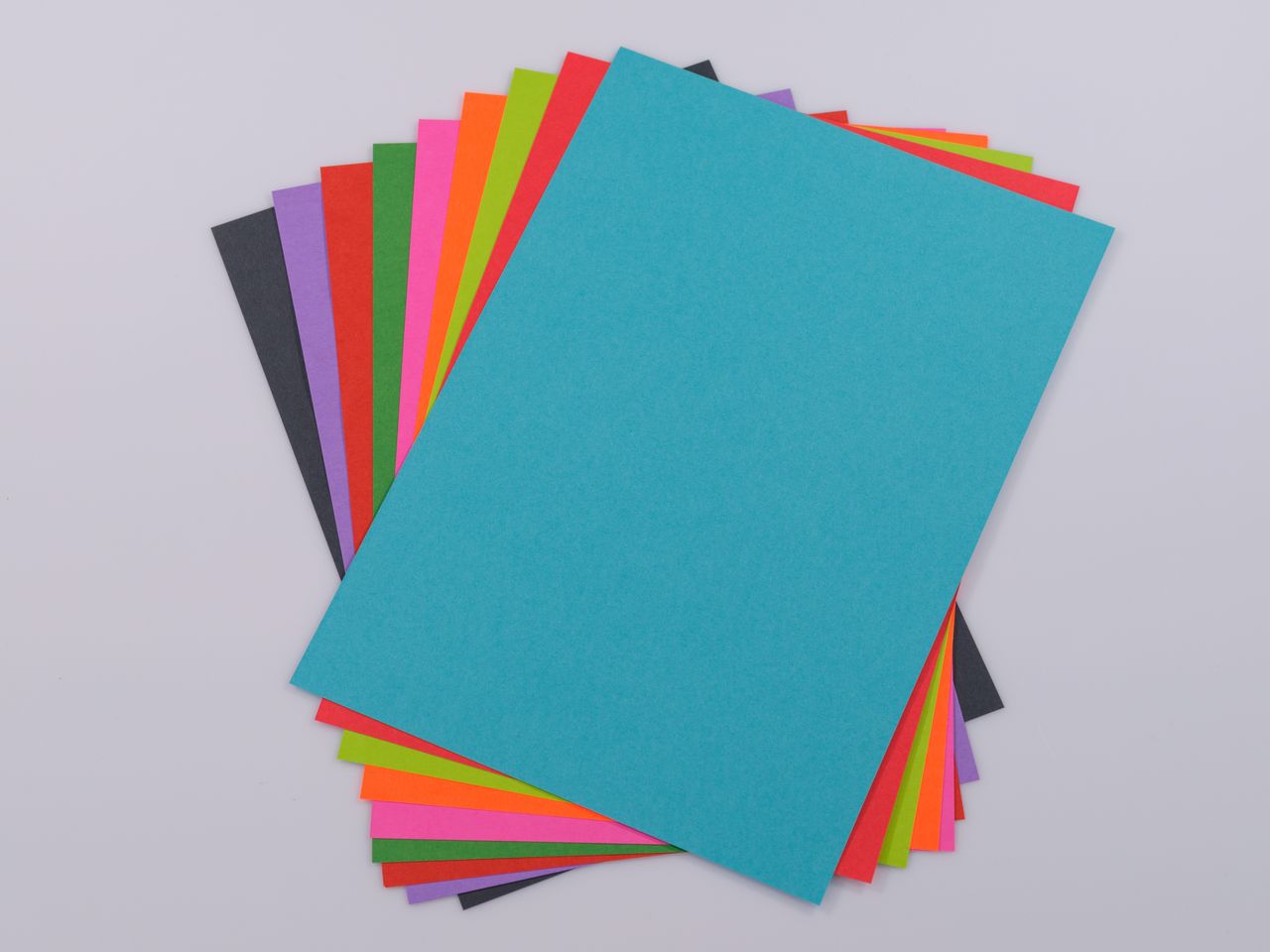 High-quality vibrant colored paper stack on a neutral white background, perfect for creative projects.