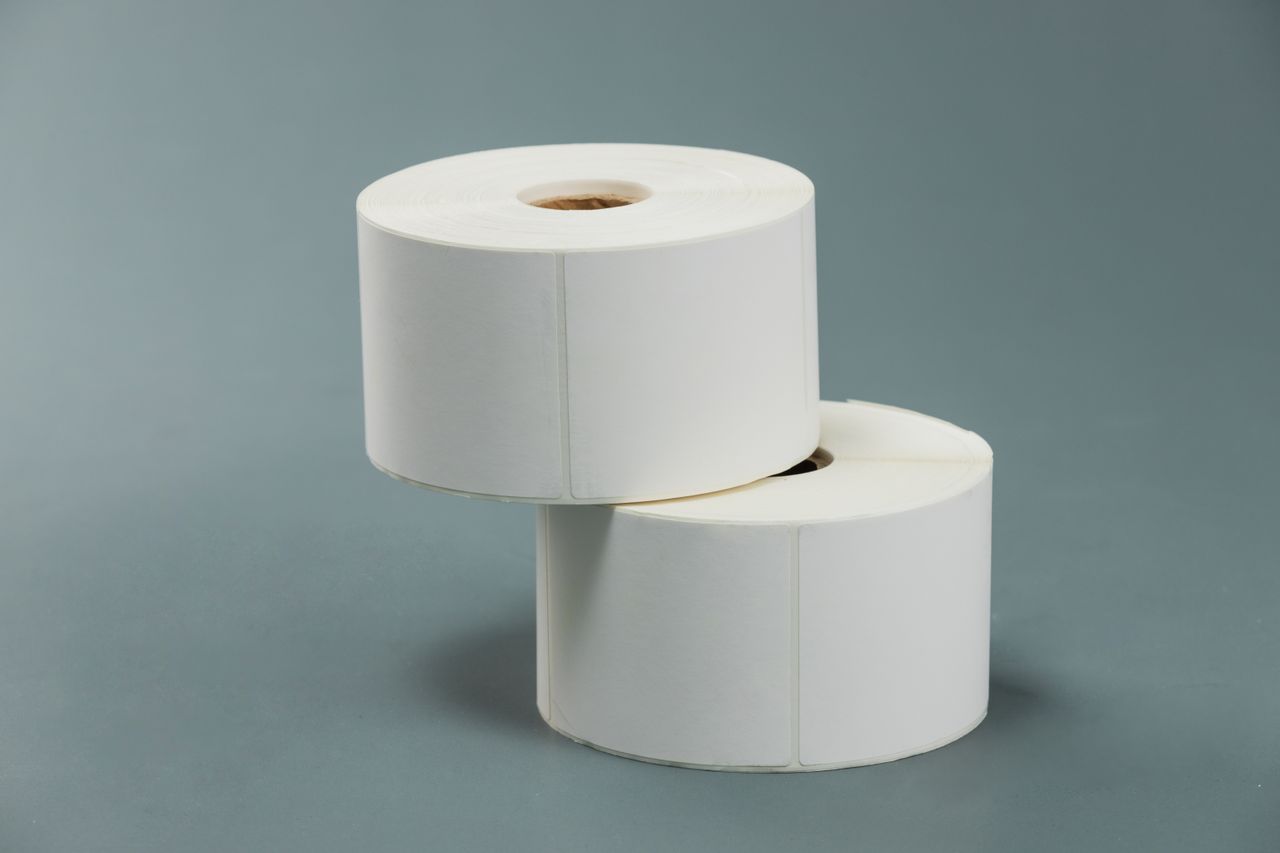 A minimalist composition of two white paper rolls stacked against a grey backdrop.