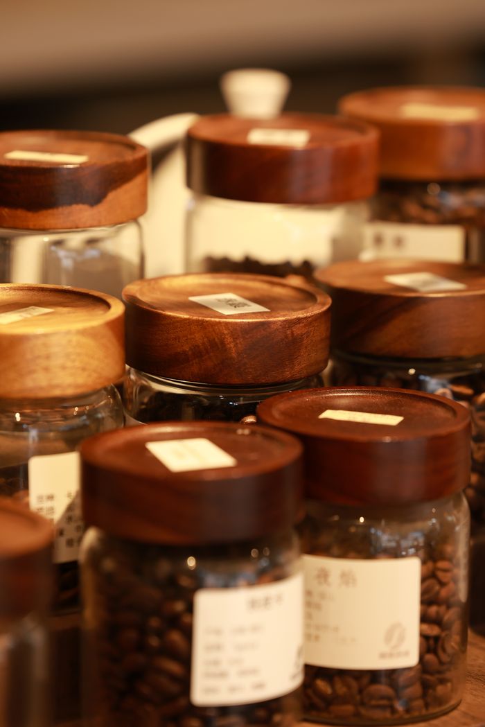 Close-up of glass jars filled with coffee beans, wooden lids, labels.